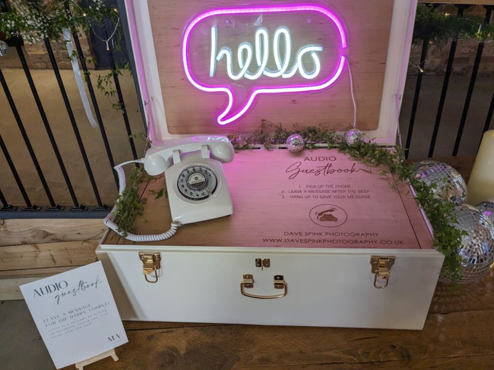 suitcase and retro phone with neon 'hello' sign at barn wedding in York